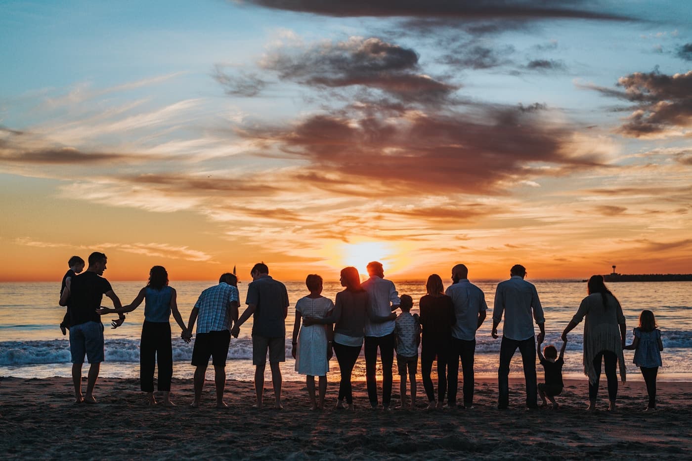 A big family holding hands on the beach at sunset
