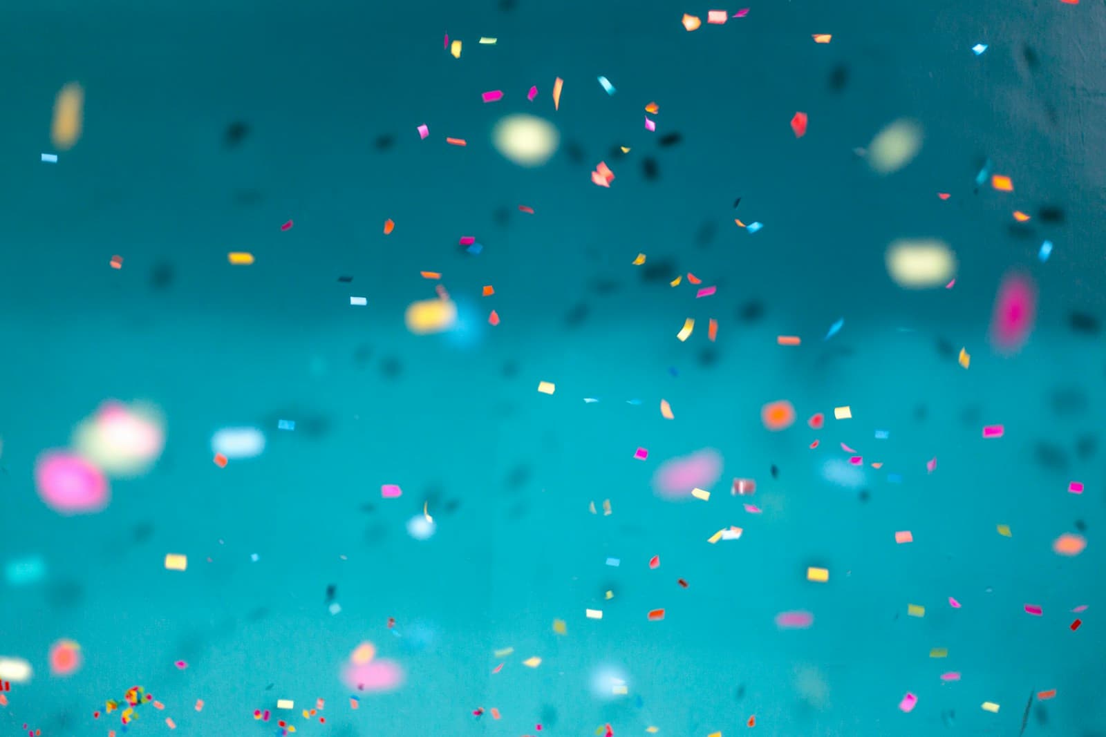 Colorful confetti falling against a bright teal background